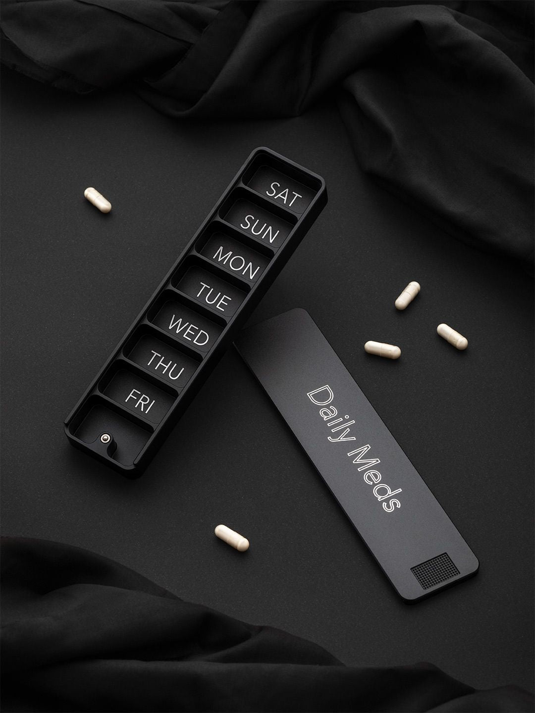 Matte black Ikigai weekly pill case engraved with Daily Meds