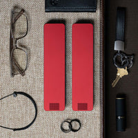 Two Designer Red Weekly Pill Cases laying next to glasses, keys, a wallet, rings, and lipstick.