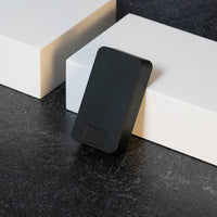 Matte Black Pill Case laying on black marble, leaning up against a white box.