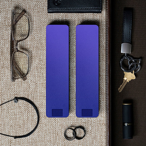 Various everyday items neatly arranged on a textured surface, including a key, wallets, and a folding knife.