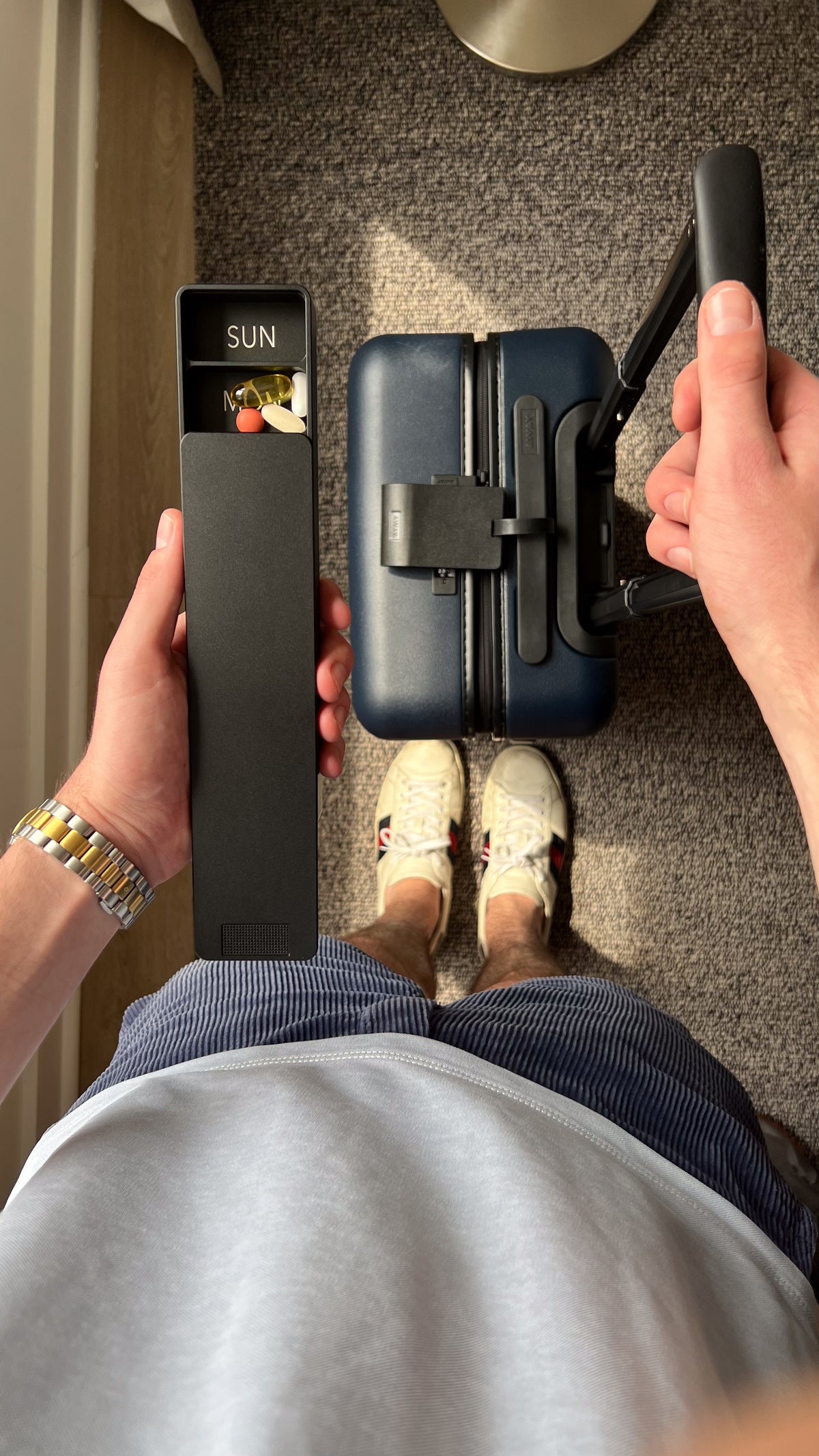 Ikigai pill case held over a carry-on suitcase
