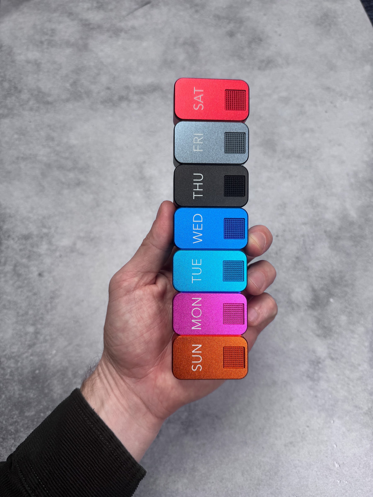 Seven single-pocket MagNano cases stacked in one hand, Sunday to Saturday