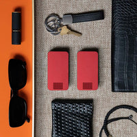 Two Designer Red Travel Pill Cases laying next to a coin purse, women's sunglasses, lipstick, wallet and keys.