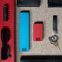 One Bahama Blue Weekly Pill Case and One Designer Red Travel Pill Case laying next to items for a ladies purse.