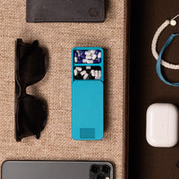 Teal pill case with two compartments open. The compartments are full of pills. There is an IPhone, Airpods, A Wallet, and Sunglasses.